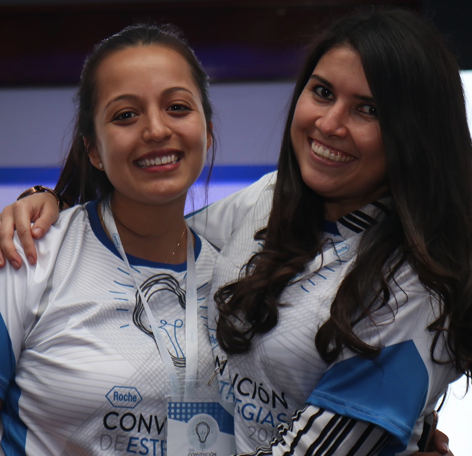 Dos compañeras de equipo abrazadas durante una convención corporativa